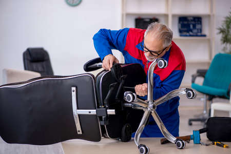 Old male repairman repairing office chairの写真素材