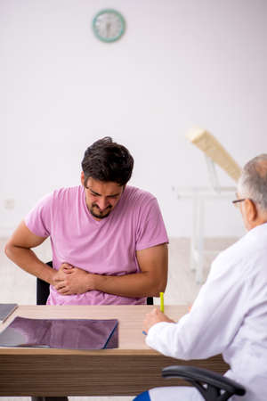 Young male patient visiting old male doctorの写真素材