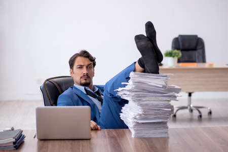 Young male employee unhappy with excessive work in the officeの写真素材