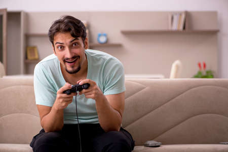Young man playing joystick games at home