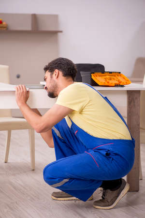 Young male carpenter repairing table at homeの写真素材