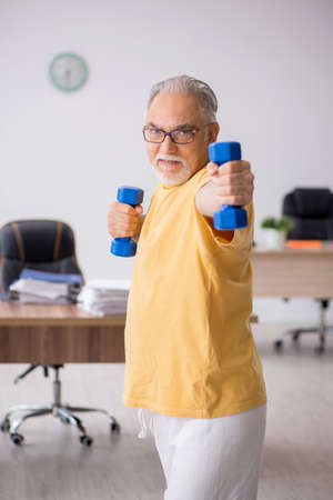 Old businessman employee doing sport exercises in the officeの写真素材