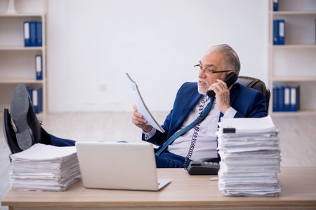 Old male employee and too much work in the officeの写真素材