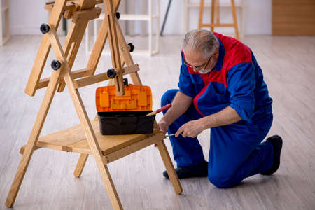 Old male carpenter repairing drawing easelの写真素材