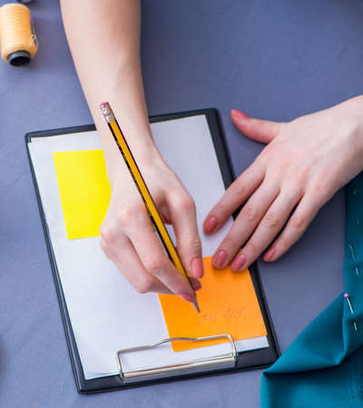Woman tailor working on a clothing sewing stitching measuring fabricの写真素材