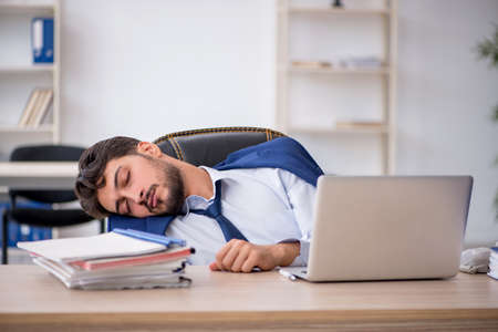 Young male employee extremely tired in the officeの写真素材
