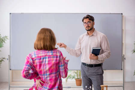Young male teacher and redhead girl in the classroom