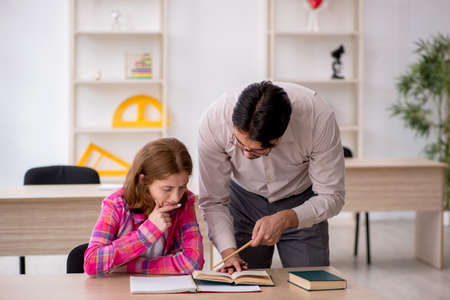 Young male teacher and redhead girl in the classroomの写真素材