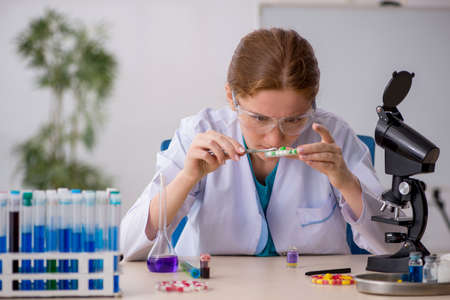 Young female chemist in drugs synthesis concept
