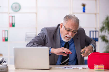 Old male employee cutting his hand in the officeの写真素材