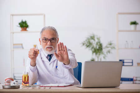 Old male doctor dentist working in the clinicの写真素材