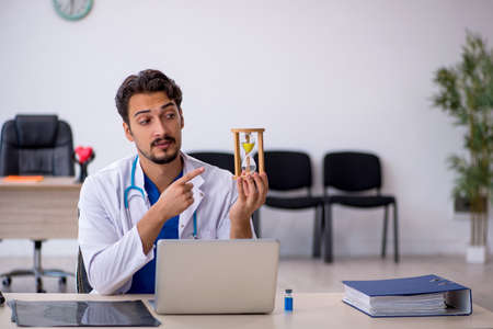 Young male doctor in time management conceptの写真素材