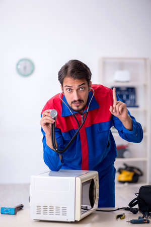 Young male repairman repairing oven at workshopの写真素材