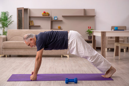 Old man doing sport exercises at homeの写真素材