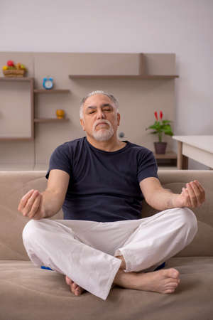 Old man doing sport exercises at homeの写真素材