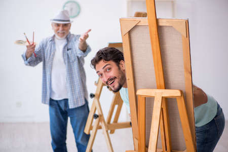 Old painter teaching young student at studioの写真素材