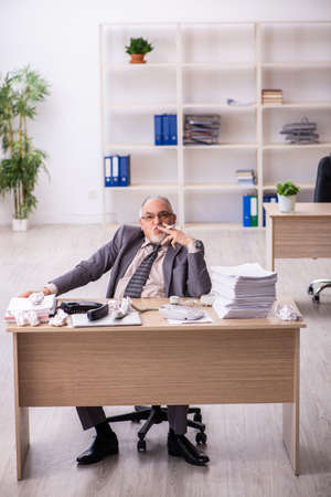 Old male employee working at workplaceの写真素材
