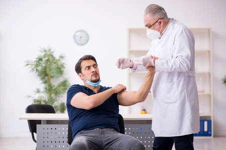Young male patient visiting old male doctor in vaccination conceの写真素材