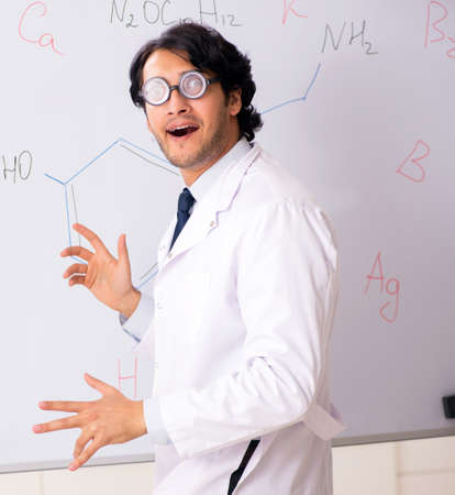 The young funny chemist in front of white board