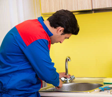 Plumber repairing tap at kitchenの写真素材