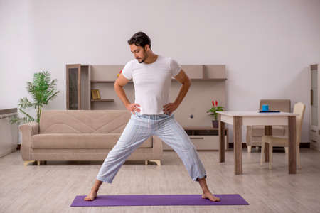 Young man doing sport exercises at homeの写真素材
