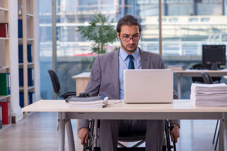 Young male employee in wheel-chair working in the officeの写真素材