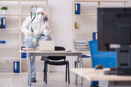 Old male contractor in office disinfection conceptの写真素材