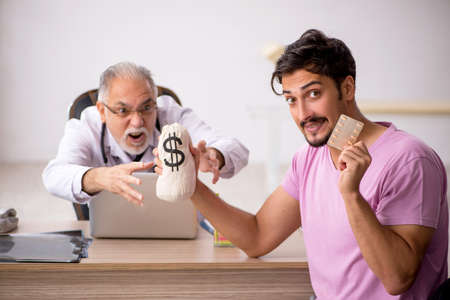 Young male patient visiting old male doctor in remuneration concの写真素材