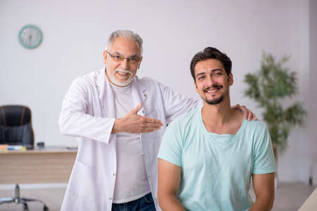 Young male patient visiting old male doctorの写真素材