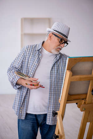 Old man enjoying painting at homeの写真素材