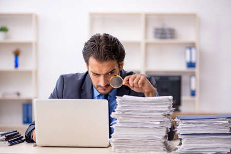 Young male employee and too much work in the officeの写真素材