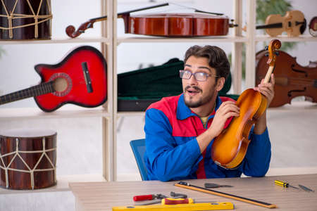 Young man repairing musical instruments at workshop
