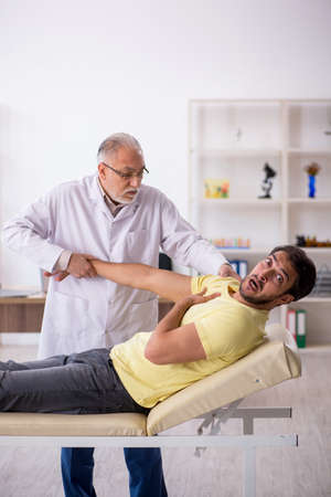 Young male patient visiting old male doctor chiropractorの写真素材