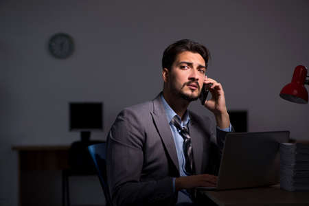 Young male employee working late in the officeの写真素材