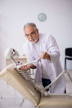 Old male doctor with skeleton in the clinicの写真素材