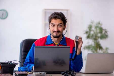 Young male repairman repairing computerの写真素材