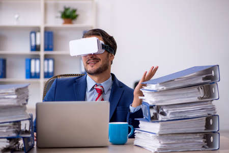 Young male employee enjoying virtual glasses at workplace
