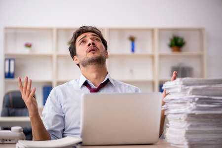 Young male employee and too much work in the office