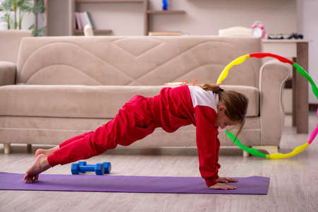 Young little girl doing sport exercises at homeの写真素材