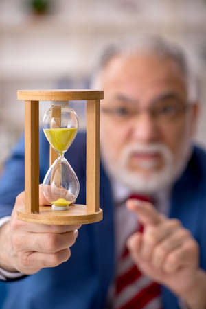 Old male employee in time management concept