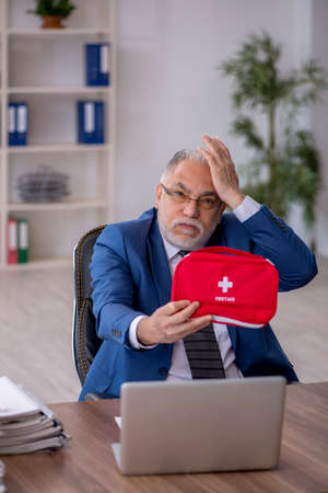 Old male employee feeling bad at workplaceの写真素材