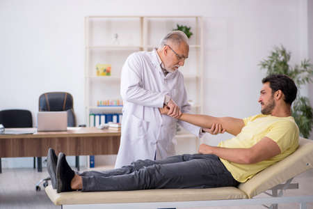 Young male patient visiting old male doctor chiropractorの写真素材