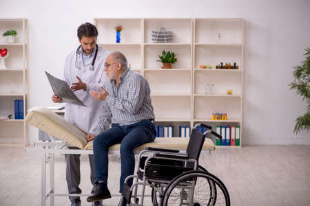 Old injured man visiting young male doctor radiologistの写真素材