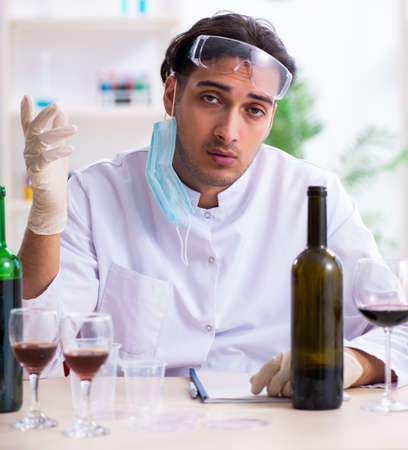 Male chemist examining wine samples at labの写真素材