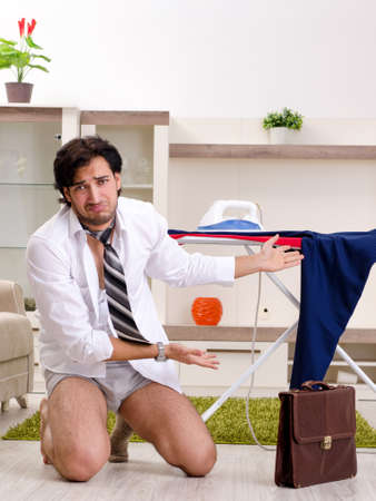 Young man ironing in the bedroomの写真素材