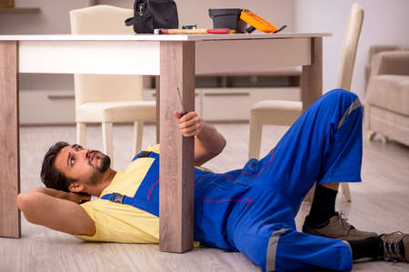 Young male carpenter repairing table at homeの写真素材