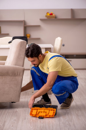 Young male carpenter repairing arm-chair at homeの写真素材
