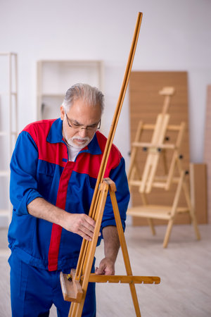Old male carpenter repairing drawing easelの写真素材