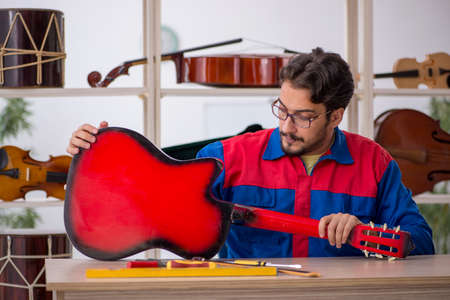 Young man repairing musical instruments at workshop