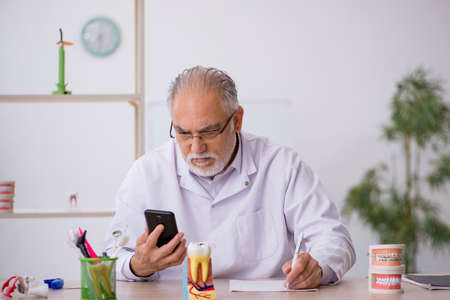 Old male dentist working in the clinic